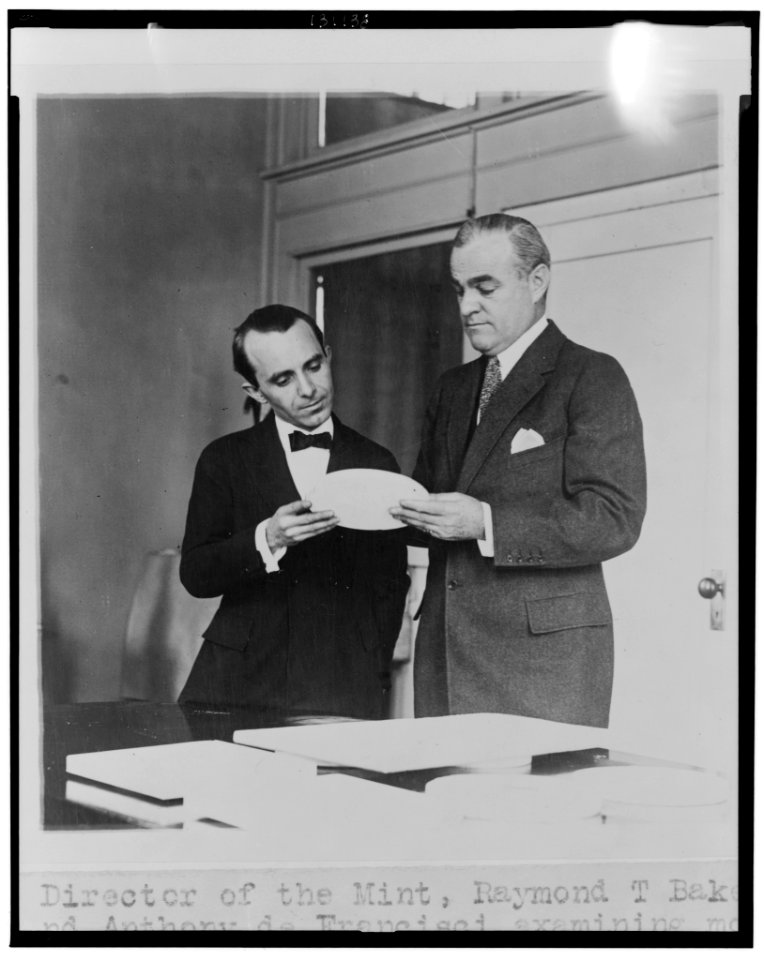 Director of the Mint, Raymond T. Baker, and Anthony de Francisci examining model of new silver dollar, the first of which will be issued by Jan. 1st LCCN2002712369