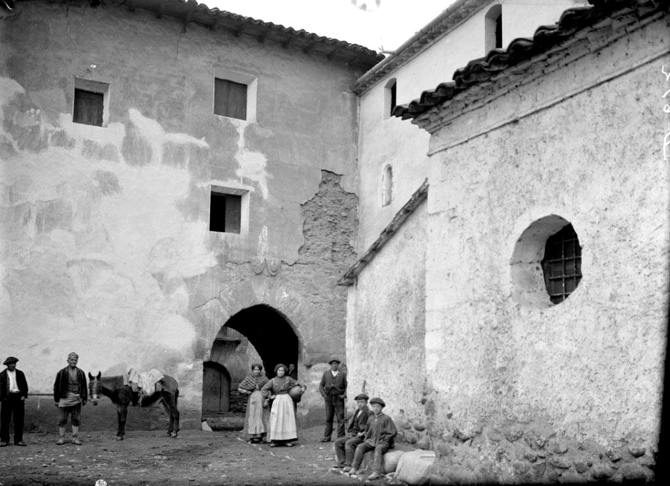 Diverses persones i un cavall davant del portal del poble de Barasona