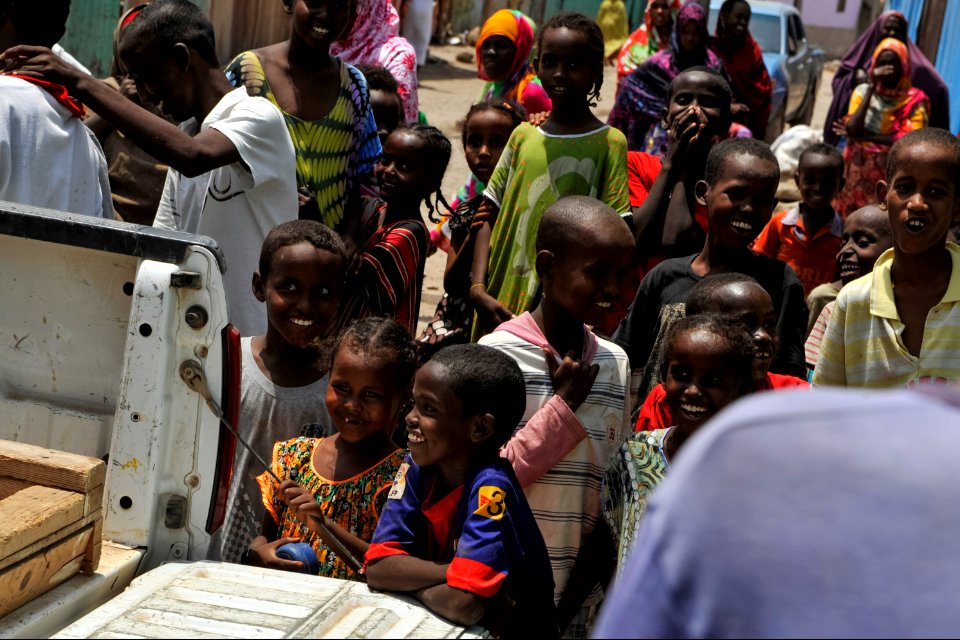 Djiboutian residents look on as donated supplies are brought into the home of a community leader in Djibouti city April 9, 2014 140409-N-LE393-115