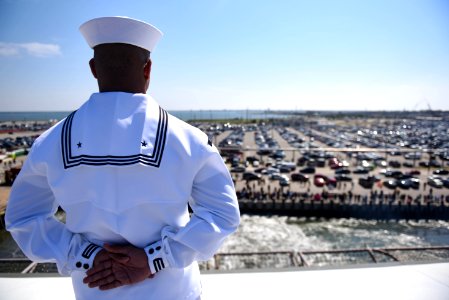 180411-N-NQ487-222 - PO3 Anthony White mans the rails aboard the aircraft carrier USS Harry S. Truman