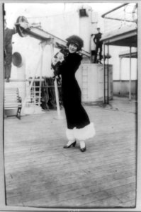 Annette Kellerman, full-length portrait, standing on deck of ship, facing front, holding a black pug (dog) LCCN96510876