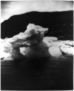 Another view of iceberg or ice formation with hole at center, off the coast of Labrador, with land visible in the background LCCN2012645569