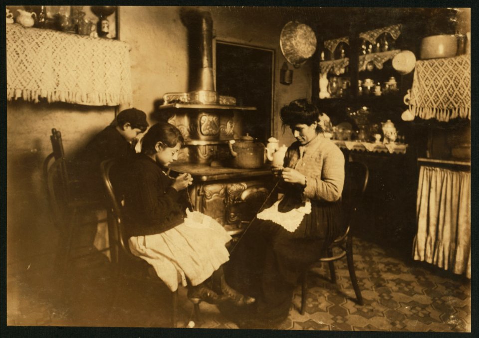 Antoinette Fazzino, ten years old, makes Irish lace for collars and waists, after school. Her younger brother (by the stove) said, 'Lace is too dam-cheap.' Antoinette wears glasses. 303 E. LOC nclc.04131