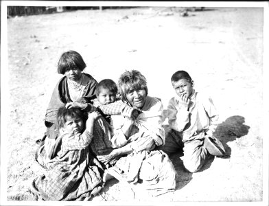 Apache Indian grandmother carrying her grandchild on her back and three others sitting nearby, Palomas Indian Reservation, 1903 (CHS-3586A)