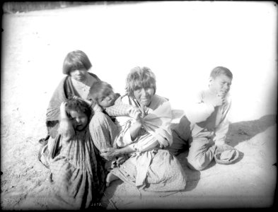 Apache Indian grandmother carrying her grandchild on her back and three others sitting nearby, Palomas Indian Reservation, 1903 (CHS-3586)