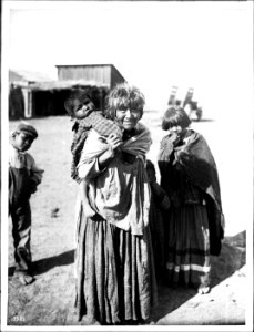 Apache Indian grandmother carrying her grandchild on her back and two others standing nearby, Palomas Indian Reservation, 1903 (CHS-3585)