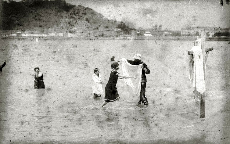 Bañero llevando la toalla a una bañista que sale del agua en la playa de la Concha (1 de 2) - Fondo Car-Kutxa Fototeka