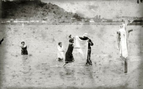 Bañero llevando la toalla a una bañista que sale del agua en la playa de la Concha (1 de 2) - Fondo Car-Kutxa Fototeka