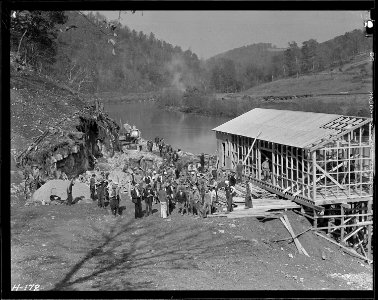 A group of workers in front of the partially constructed warehouse just below the site of Norris Dam. The cement... - NARA - 532789 photo