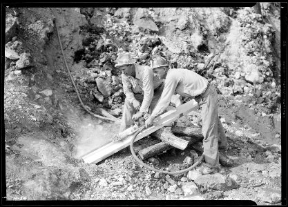 Arthur Roberts and Sam Mynatt, drilling for a shot in boulder in roadway at Norris Dam. - NARA - 532677