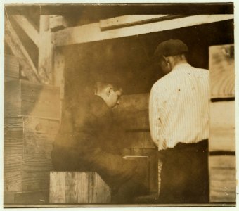 2 boys at the filling machine in Cannon's Cannery, Bridgeville, Del. These boys place cans in the grove to be filled with peas. Work 10 hours per day, and when there is a good supply of peas LOC nclc.00798