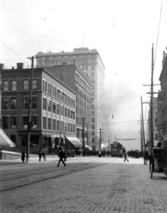 2nd Ave looking south from Columbia St toward a crowd watching a smoking building, Seattle, ca 1905 (WARNER 632)