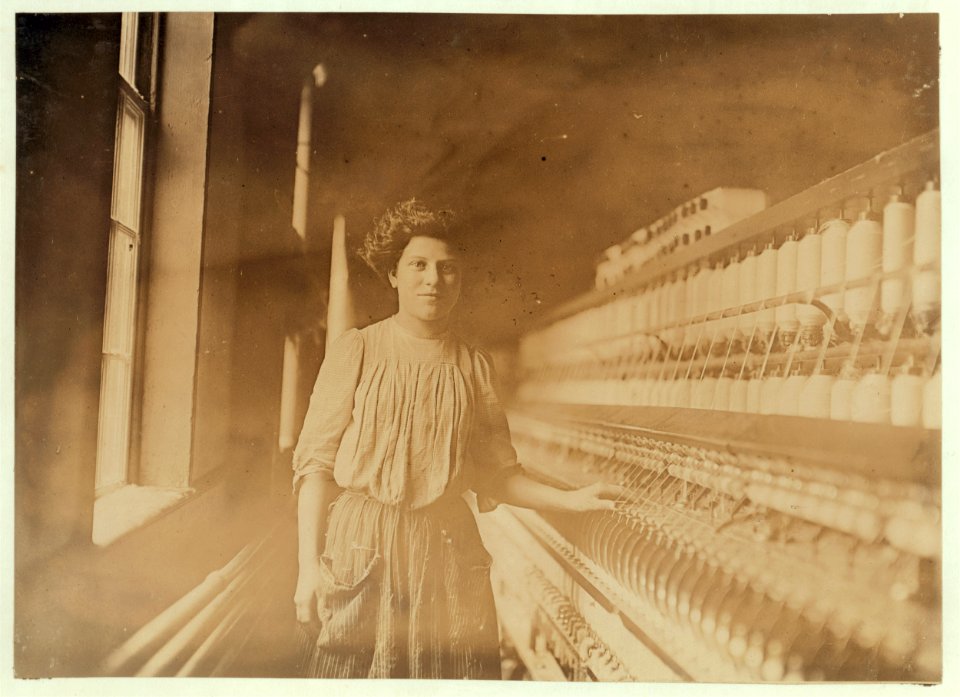 A beautiful young spinner and doffer in Interlaken Mill, Arkwirght, R. I. She has worked there 1 year. Looked 12 yrs. old and had a hectic flush caused by warm, close atmosphere. LOC nclc.01664
