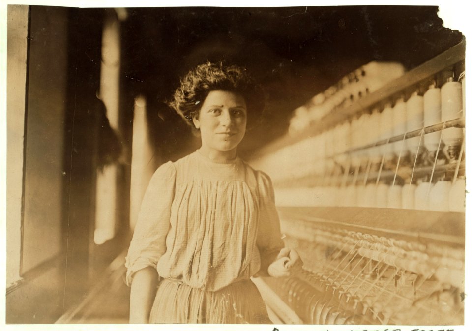 A beautiful young spinner and doffer in Interlaken Mill, Arkwirght, R. I. She has worked there 1 year. Looked 12 yrs. old and had a hectic flush caused by warm, close atmosphere. LOC cph.3b07717