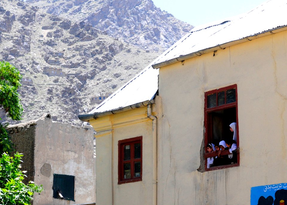 A classroom of Afghan girls look out their window as Afghan National Civil Order Police patrolmen carry boxes of supplies to distribute to the students. (4678254214)