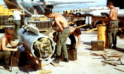 Armorers load 20mm cannon rounds into an F-4 gun pod