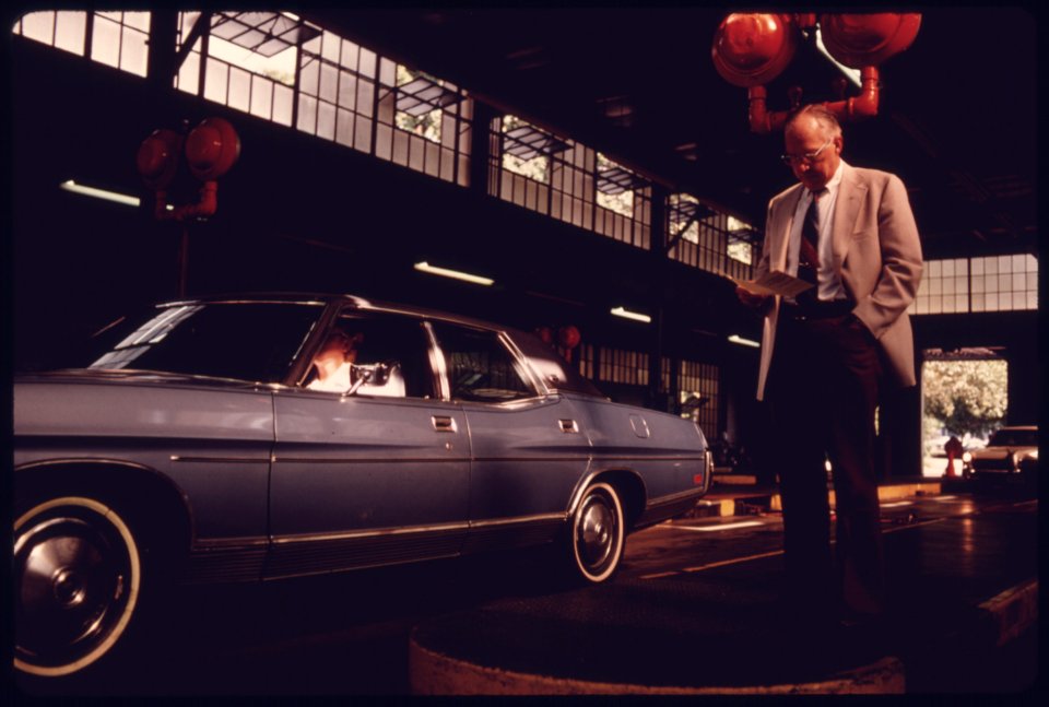 As His Car Is Being Tested, a Motorist Reads over a Free Brochure on Exhaust Emissions at an Auto Emission Inspection Station in Downtown Cincinnati, Ohio...08-1975 (4266537928)