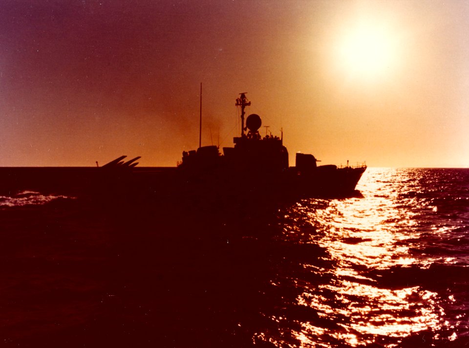 Asheville class gunboat silhouetted against the sun c1975