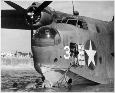 Beaching crew clings to bow line of twin-engine patrol bomber seaplane at Naval Air Station in Banana River, Florida - NARA - 520920
