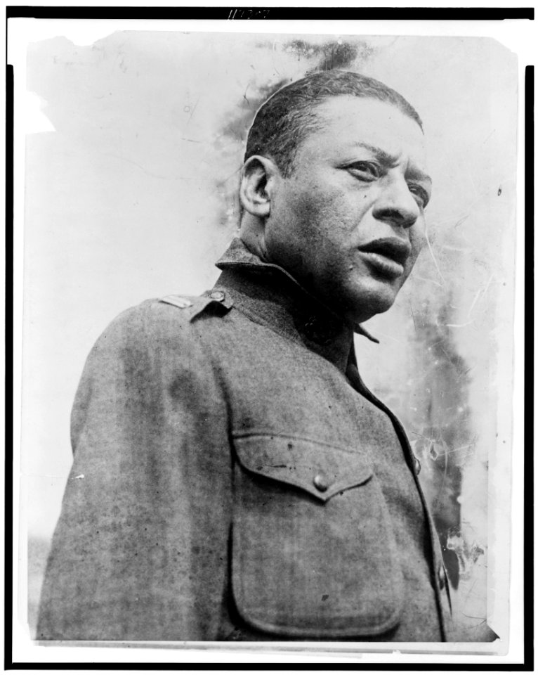Bert Williams, head-and-shoulders portrait, standing, facing right, singing a psalm at the first regimental open air service for the 15th Regiment of the New York National Guard, held in LCCN96521643