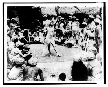 Between savage and tiger. Nautch girl dancing on rug with Hindoo men and women watching LCCN2003675560