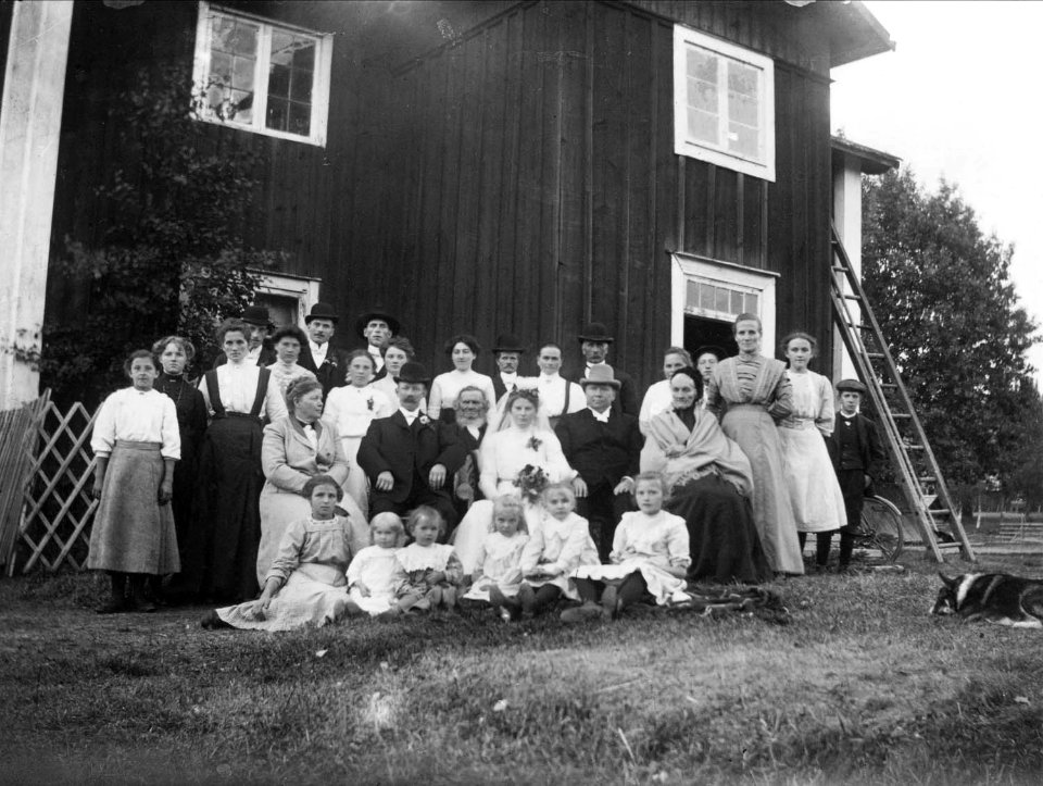 Bröllop i Lispa. Gruppbild med brudpar sittande i mitten - Nordiska Museet - NMA.0038299