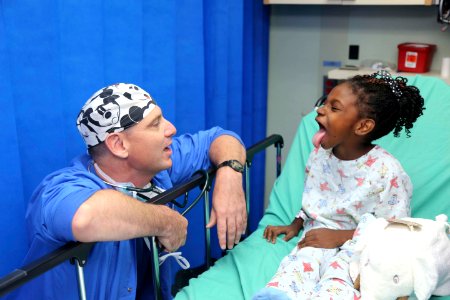 Cmdr. William Cavill examines a child before her surgery. (20318997075) photo