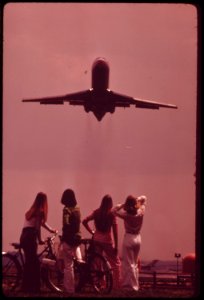Bicyclist-holds-ears-as-jet-aircraft-roars-off-from-national-airport-nearby-are-a-marina-and-a-waterfowl-sanctuary-may-1973 7461397676 o