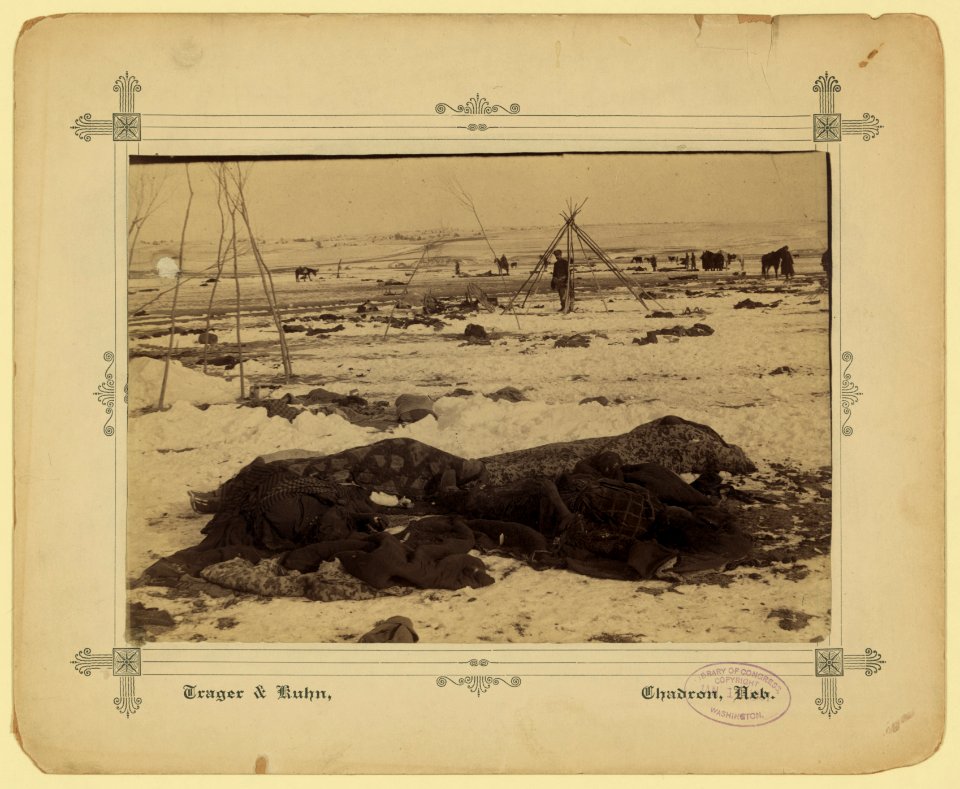 Big Foot's camp three weeks after the Wounded Knee Massacre (Dec. 29, 1890), with bodies of several Lakota Sioux people wrapped in blankets in the foreground and U.S. soldiers in the LCCN2007678212