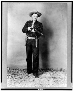 Bill Bennett, full-length portrait, standing, facing slightly right, holding rifle LCCN91787981