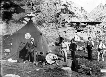 Campament de cacera amb una tenda de campanya i dos homes portant un isard mort