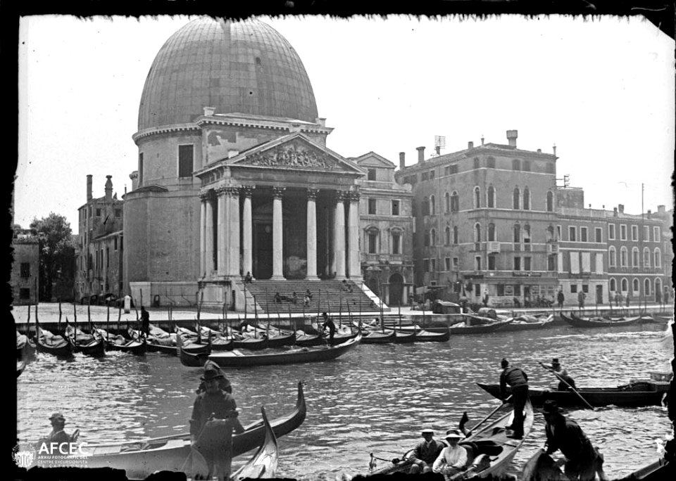 Canal de Venècia amb barques i gent i al fons un edifici amb una gran cúpula