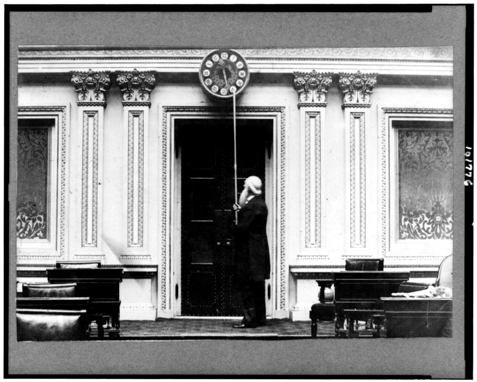 Capt. Isaac Bassett, employee of U.S. Senate for over 60 years, turning back the hands of the Senate clock at close of a session of Congress) - Harry O. Hall LCCN90713442