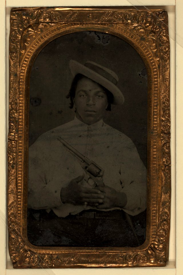 Black man, civilian, holding colt army revolver, ring on pinky finger, dred locks LCCN2002719393