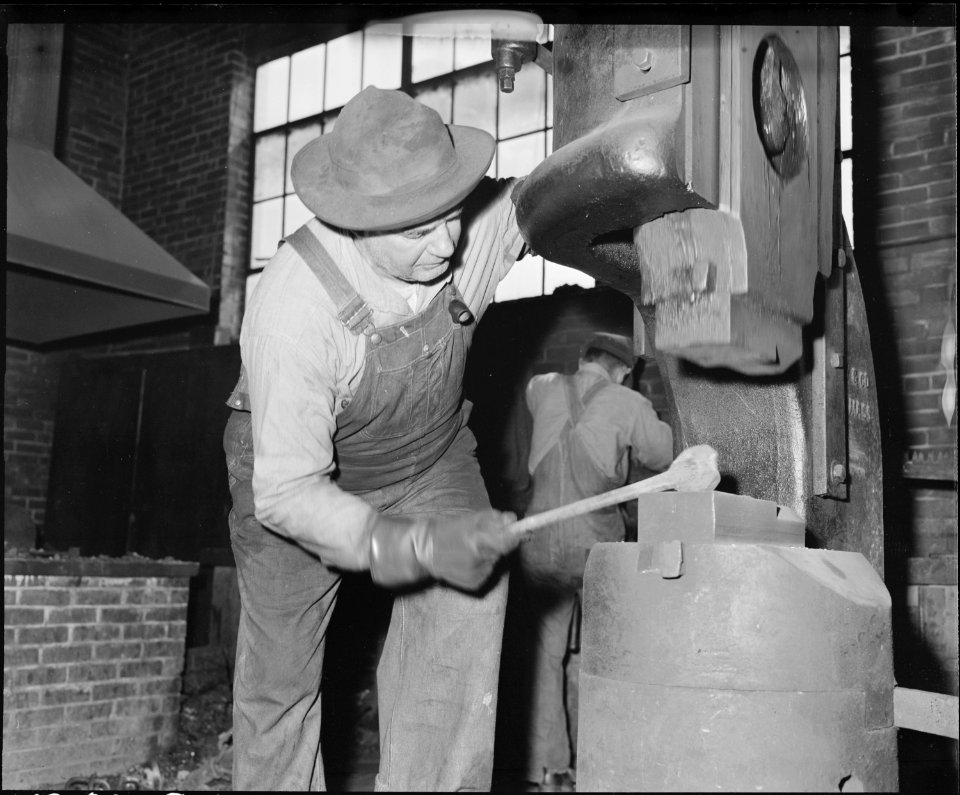 Blacksmith using hammer to shape piece of heated iron. The Pocahontas Corporation, Mines 33-34, Bishop, Tazewell... - NARA - 541075