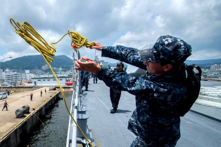 Boatswain's Mate Seaman Andre Procunier, from Riverton, Utah, throws a heaving line from the guided-missile cruiser USS Mobile Bay (CG 53) to the pier as the ship prepares to moor in Sasebo to participate in Malabar 2016