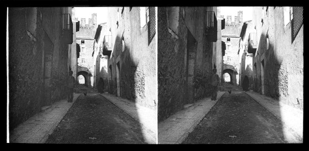 Carrer amb un home i al fons la porta-torre de Santa Jordi de Montblanc