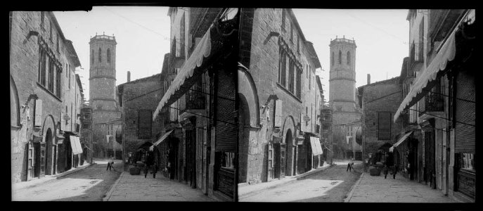 Carrer del Carme de Tàrrega amb persones i la torre d'un campanar al fons