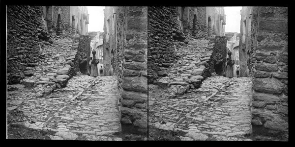 Carrer del poble d'Àger amb una dona portant un càntir al cap