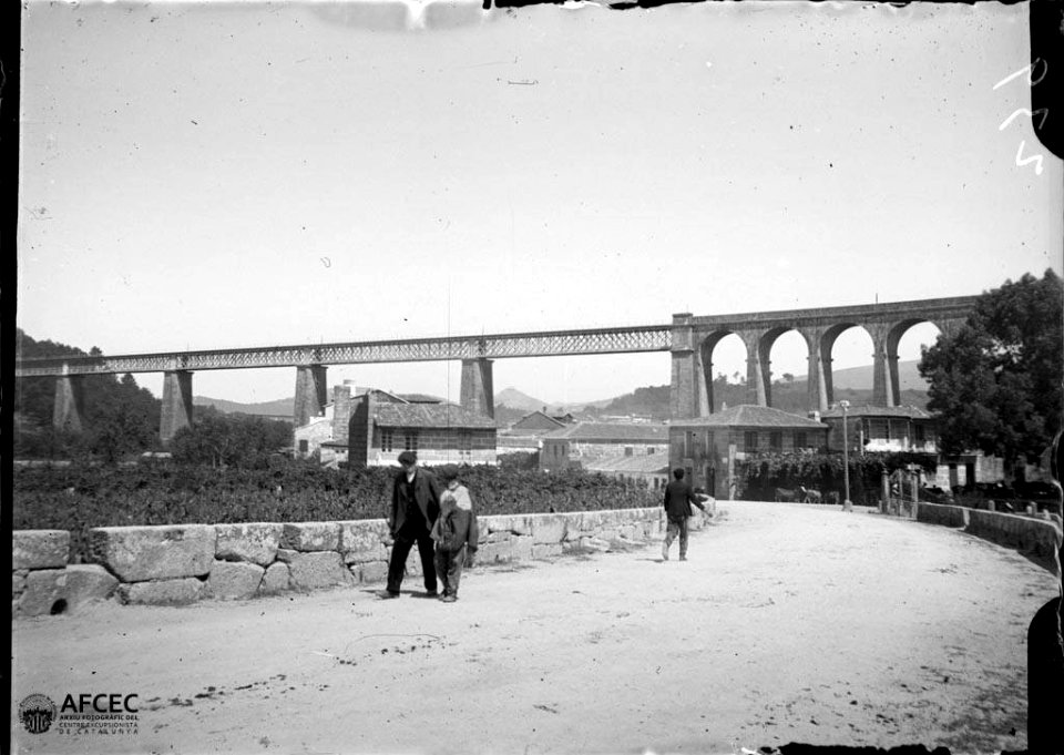 Carrer de Redondela amb gent i al fons un viaducte