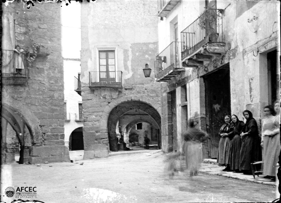 Carrer porxat de Balaguer amb un grup de dones en primer terme