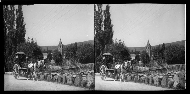 Carro amb gent i al fons vista del campanar d'Ur