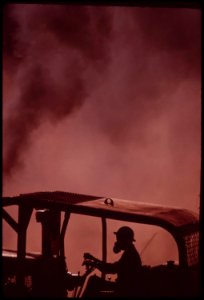 Caterpillars-work-in-dust-and-soot-hauling-logs-to-landing-area-where-they-will-be-loaded-onto-trucks-face-mask-filters-ash-and-soot-filled-air-so-driver-can-breathe-september-1973 7153115769 o