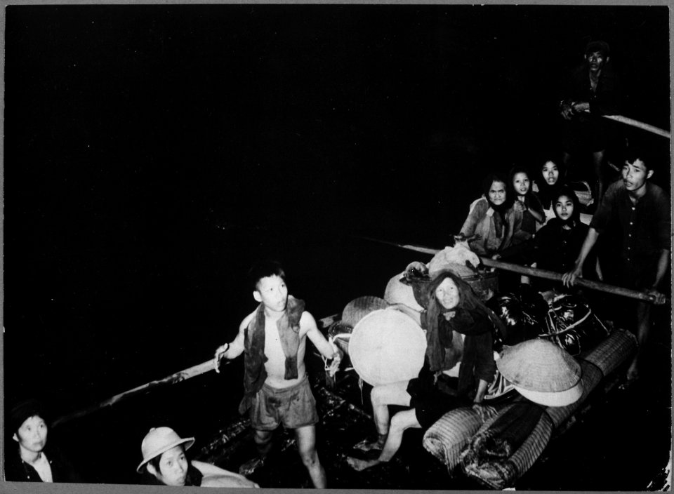 Catholics escaping communist territory in the dead of night smile as they pull alongside French landing craft that will - NARA - 541972