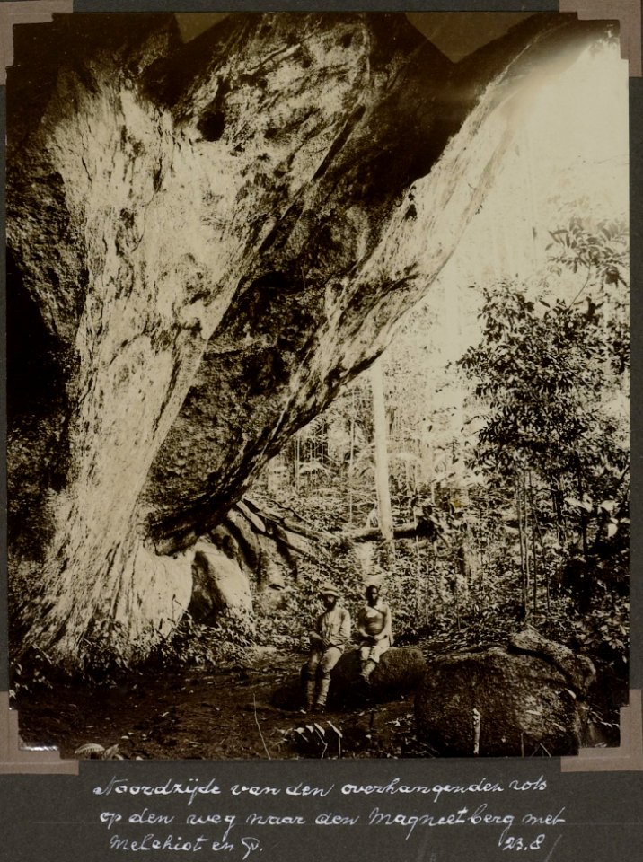 Collectie NMvWereldculturen, RV-A103-1-46, 'Noordzijde van den overhangenden rots op den weg naar den Magneetberg met Melchiot en G.M. Versteeg'. Foto- G.M. Versteeg, 23 augustus 1904