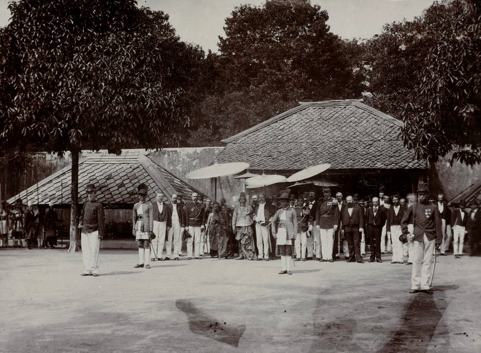 Collectie NMvWereldculturen, RV-A142-1-12, Foto, 'Groepsportret van gezelschap in de Kraton van Yogyakarta met onder de pajung de Sultan tijdens de Garebeg-feesten', fotograaf K. (Kassian) Céphas, ca. 1885