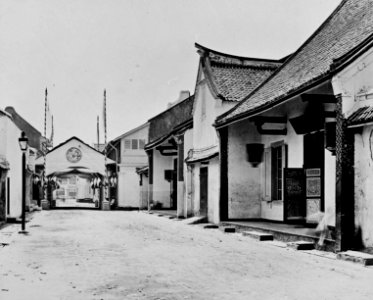 Collectie NMvWereldculturen, TM-60040271, Foto, 'Straatgezicht met een met Nederlandse vlaggen versierde poort in de Chinese wijk van Soerabaja', fotograaf onbekend, 1870-1900