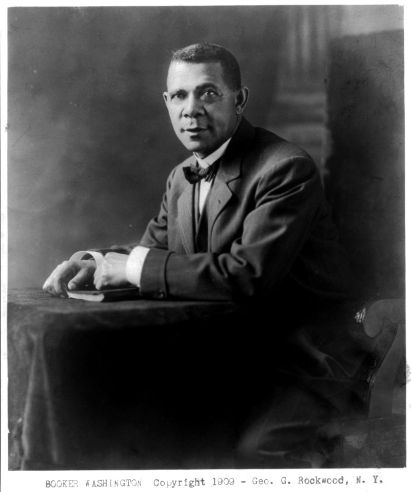 Booker Taliaferro Washington, 1865-1915, three-quarters length, seated at small table, facing slightly left LCCN2005679816
