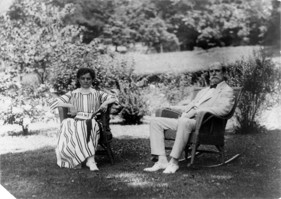 Charles Evans Hughes, full-length portrait, seated in rocker on lawn, facing left, with wife LCCN96508832