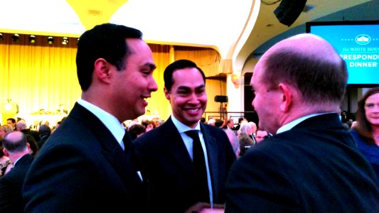Congressman Joaquin Castro of Texas, left, and his identical twin, Secretary of Housing Julian Castro, chat with Sen. Chris Coons of Delaware at the White House Correspondents Association dinner in Washington, April 30, 2016